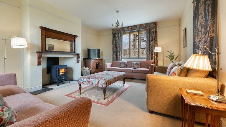 The sitting room at 6 High Hazels, with three sofas, television and a woodburner, Derbyshire